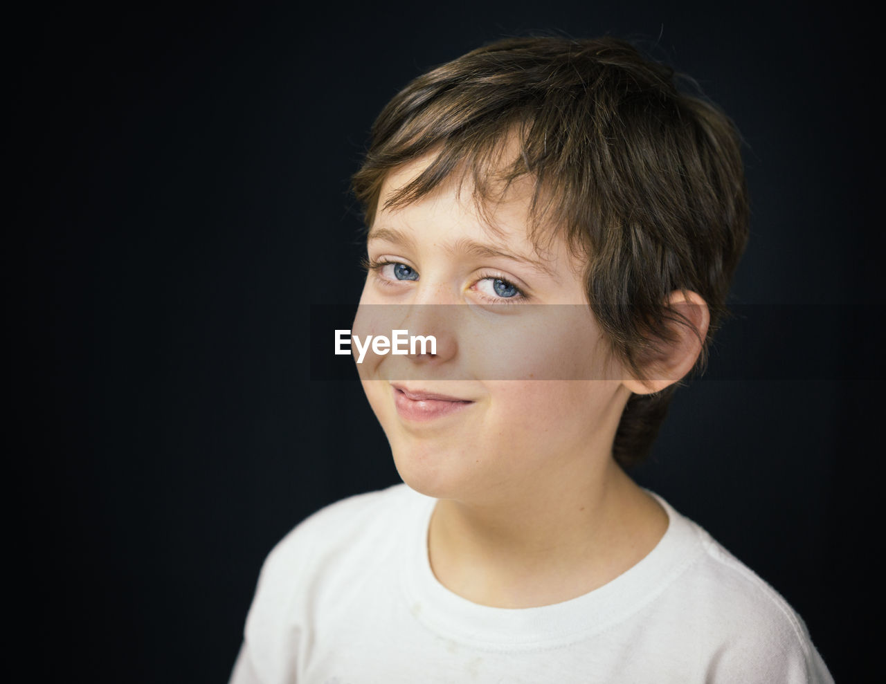 Portrait of smiling boy against black background