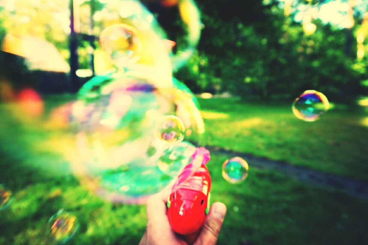 Cropped image of hand playing with toy bubble gun at park