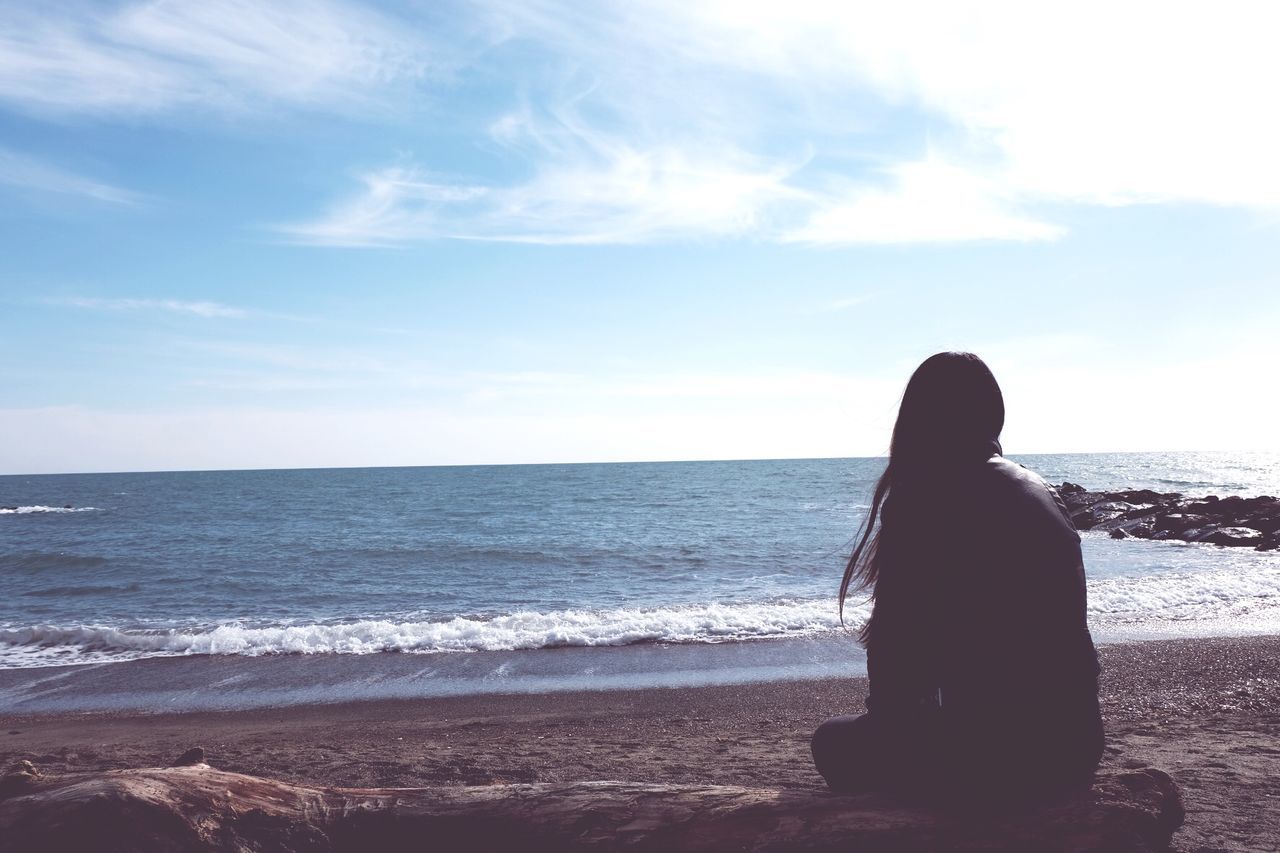 Rear view of woman sitting at beach