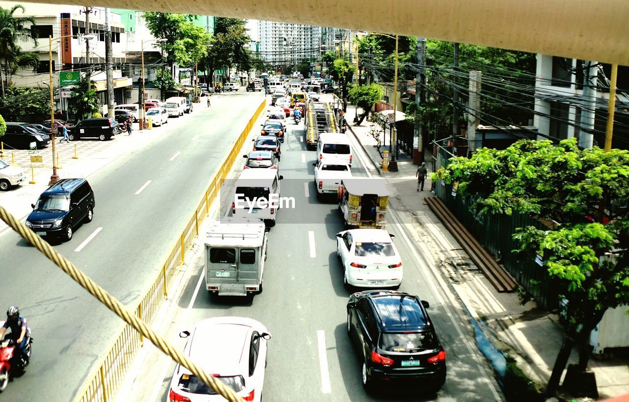 HIGH ANGLE VIEW OF CARS ON ROAD ALONG BUILDINGS