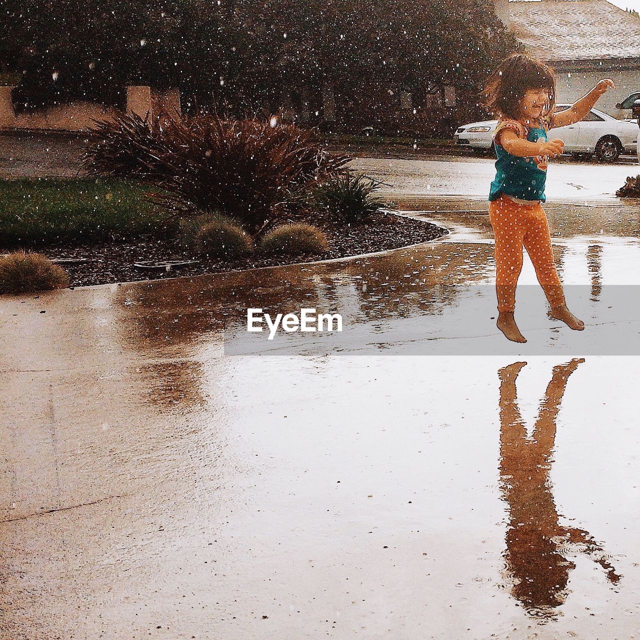 Girl jumping in rain on wet street