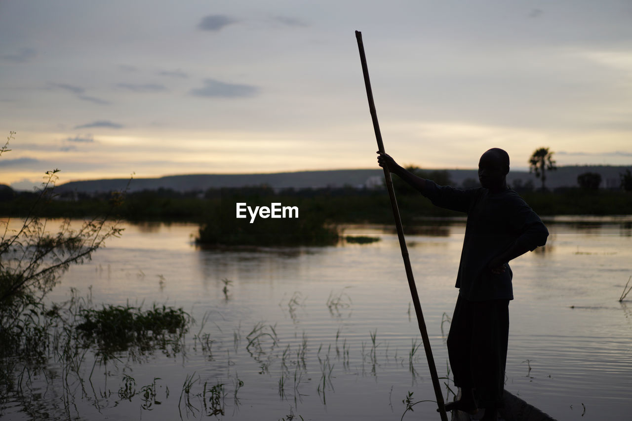 SILHOUETTE MAN FISHING IN LAKE AGAINST SKY