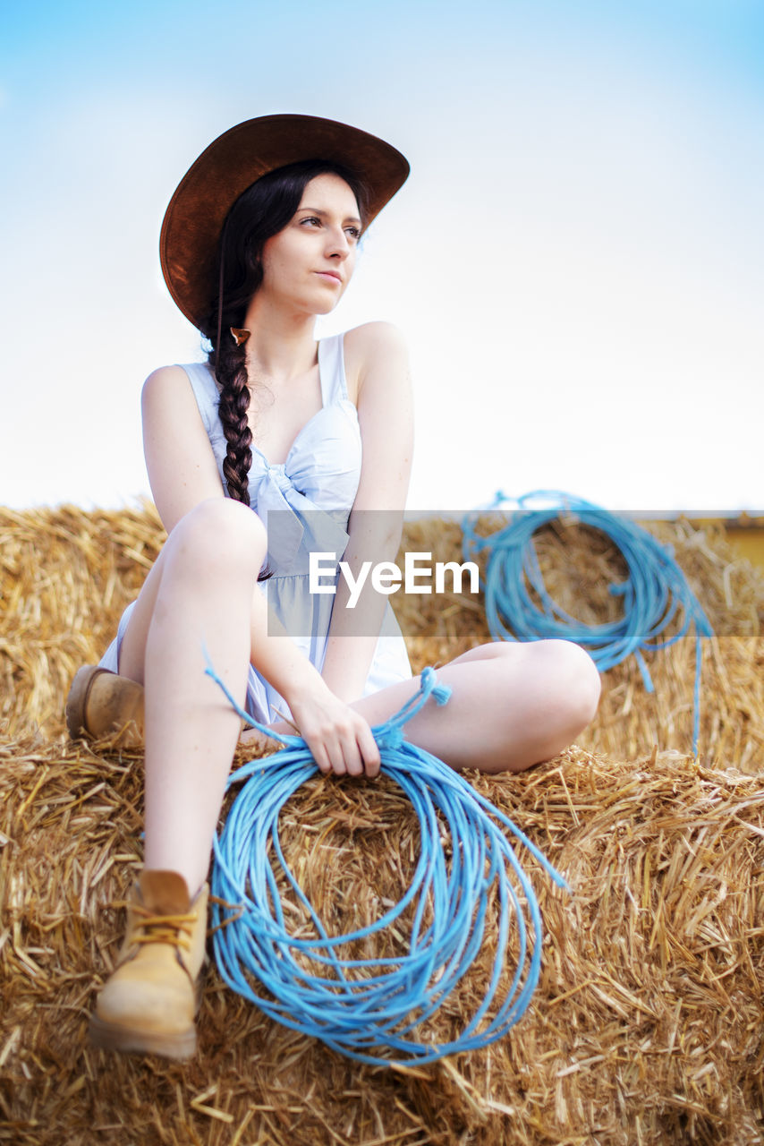 Woman in cowboy hat sitting on hay