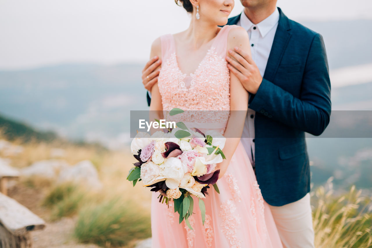 Midsection of couple embracing outdoors