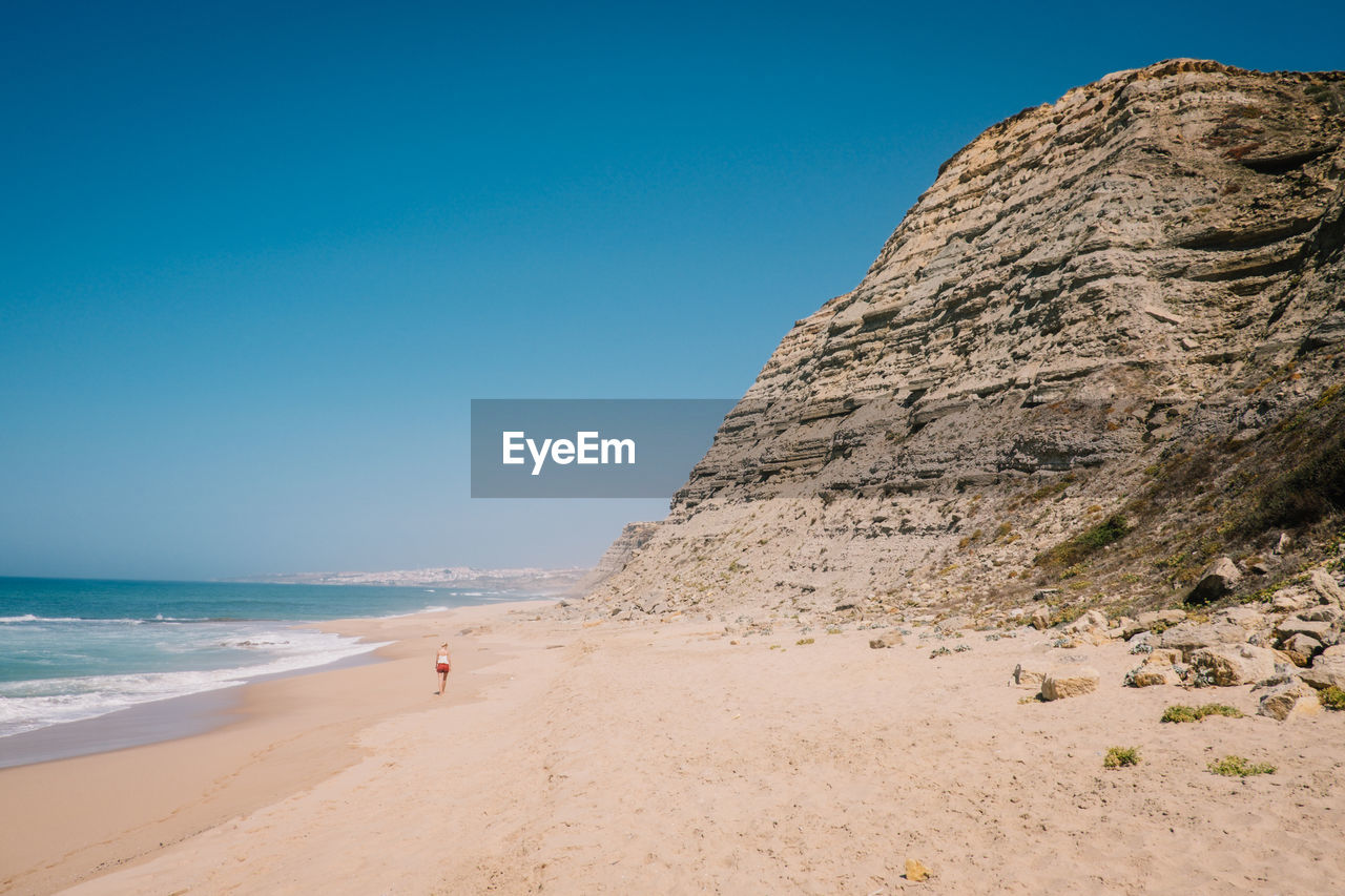 Rock formations at beach against blue sky