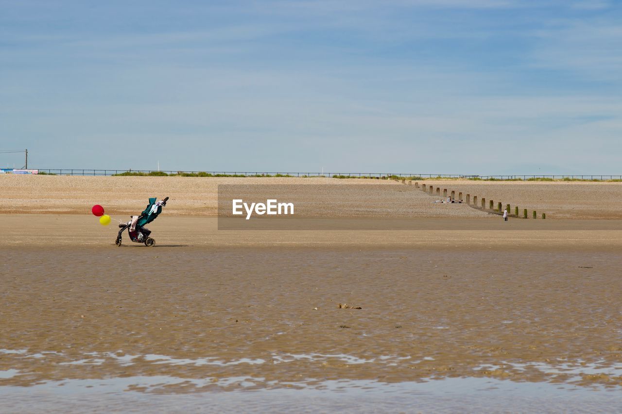 Baby carriage at beach against sky