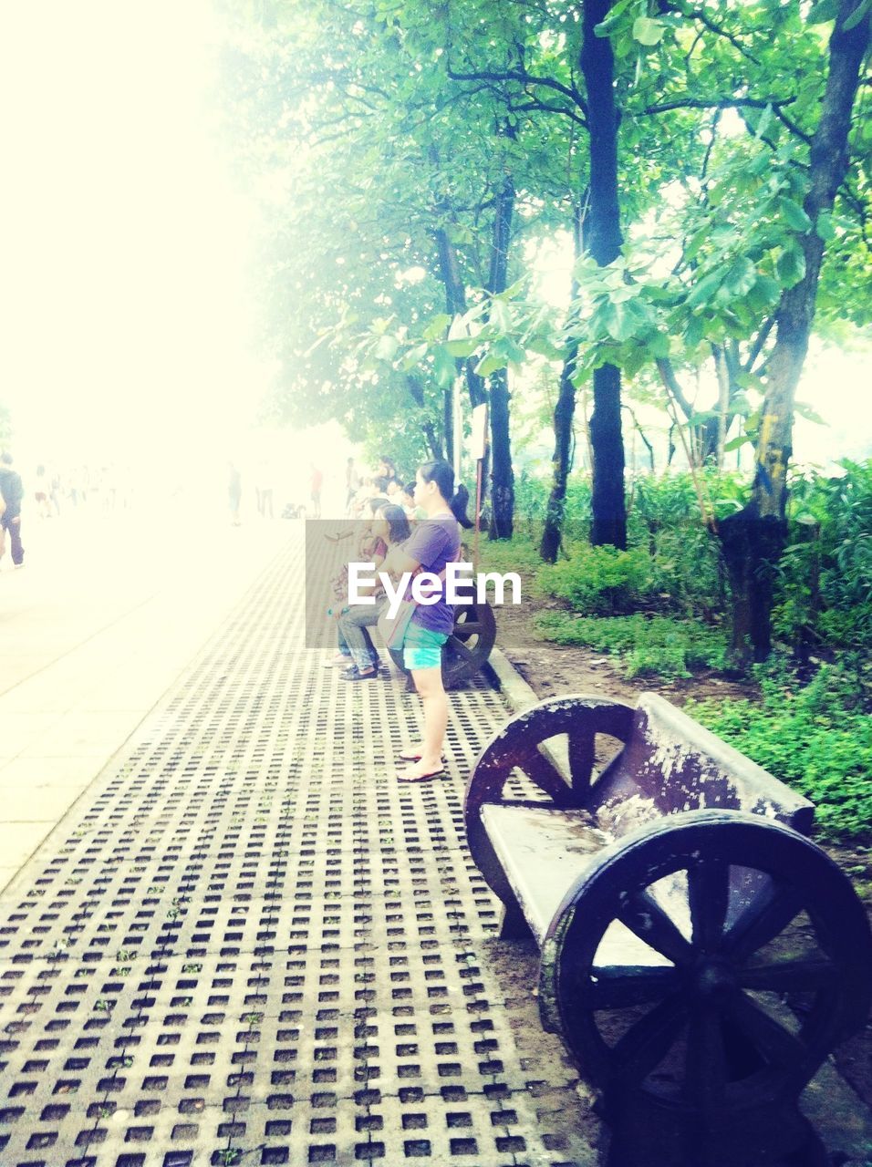 People on sidewalk in park against clear sky