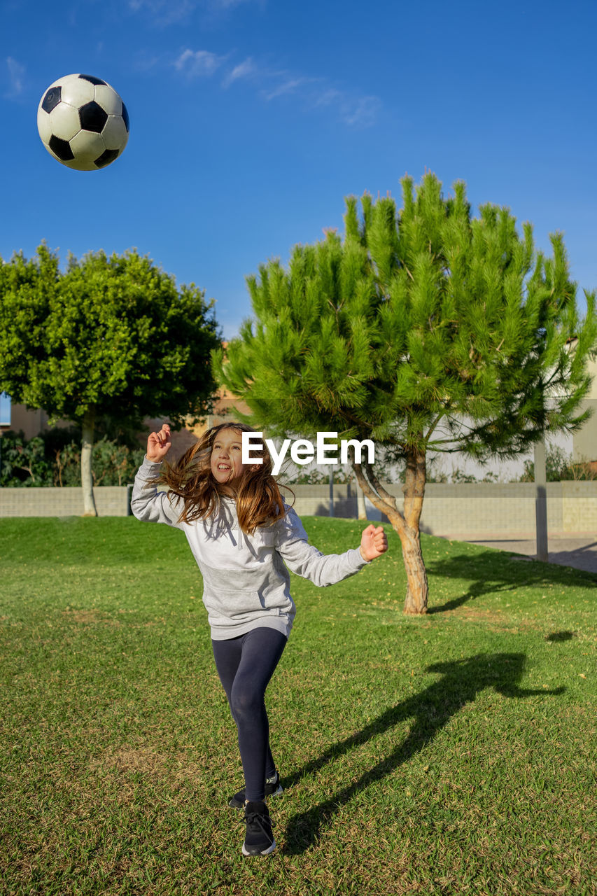 Full length of girl playing soccer ball on grass