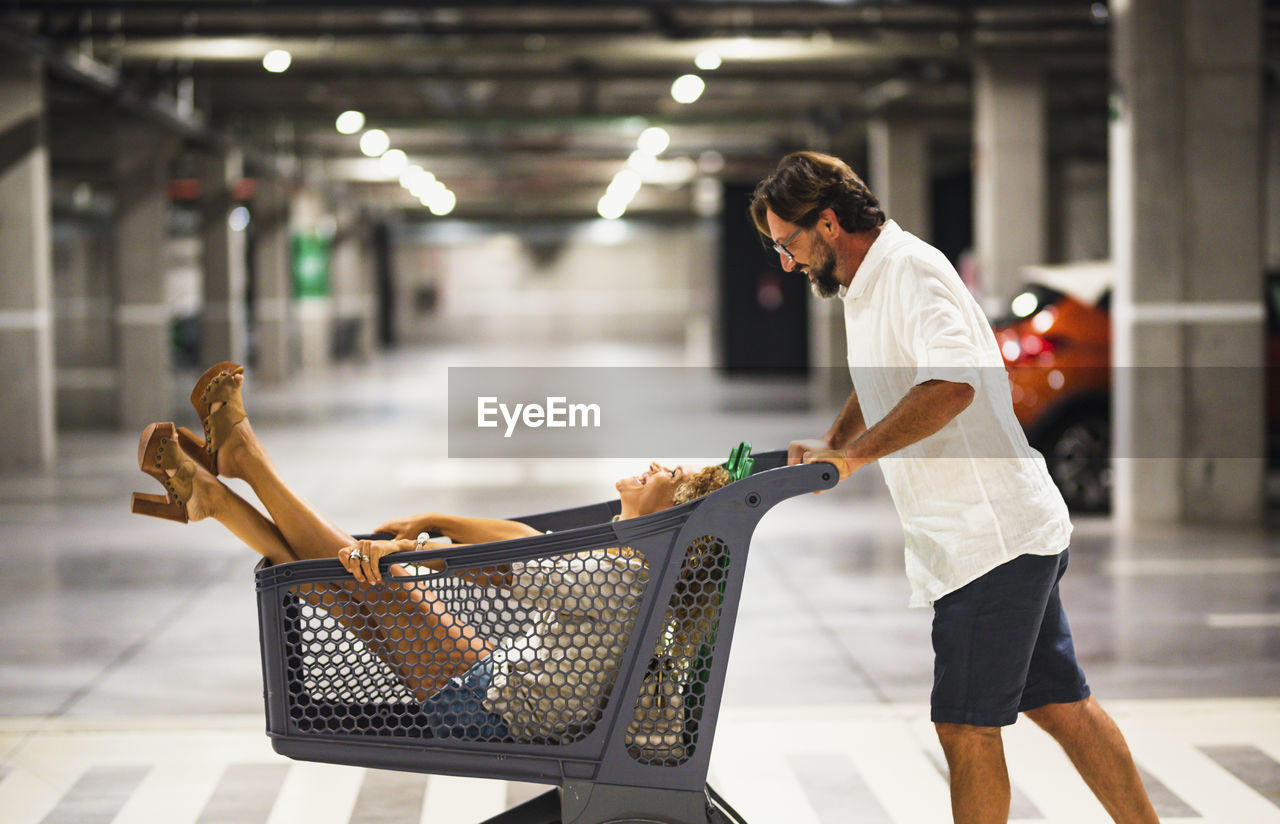 Man carrying wife in shopping cart