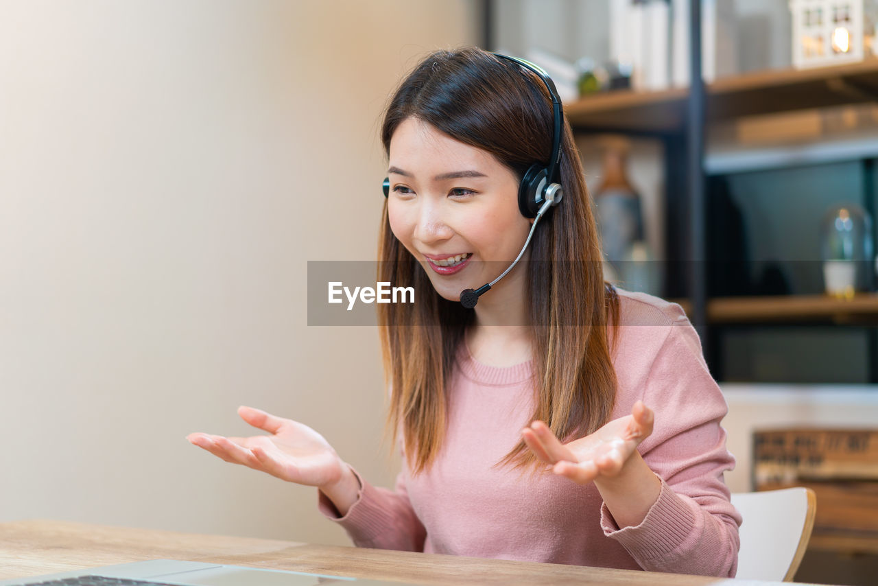 Asian woman using laptop to have video conference while working at home