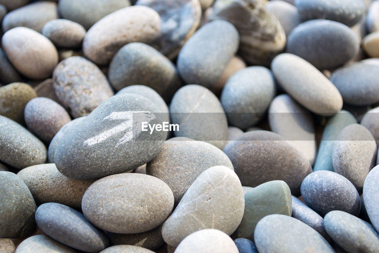 Abstract smooth round pebbles sea texture background with a white arrow pointer on the stone