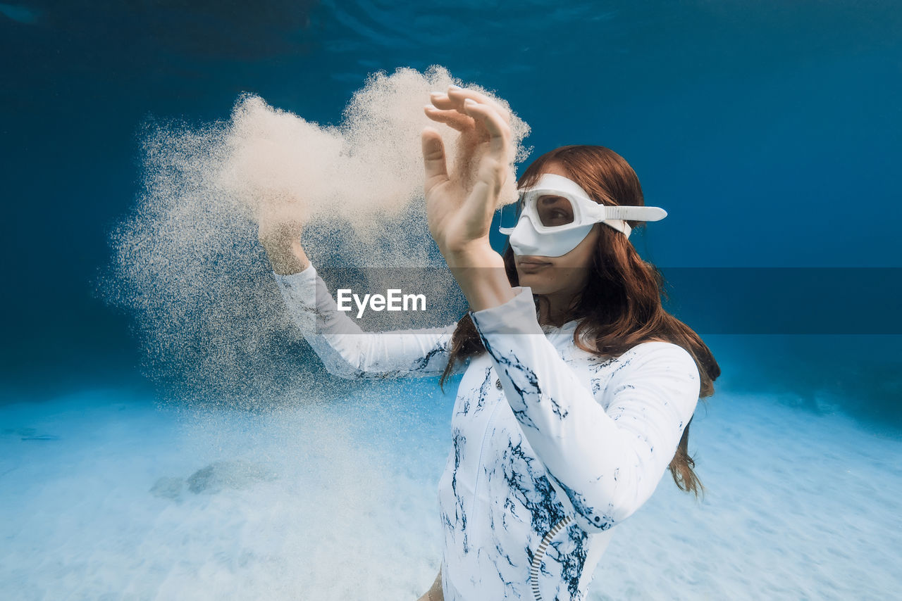 portrait of young woman wearing sunglasses while standing against sea