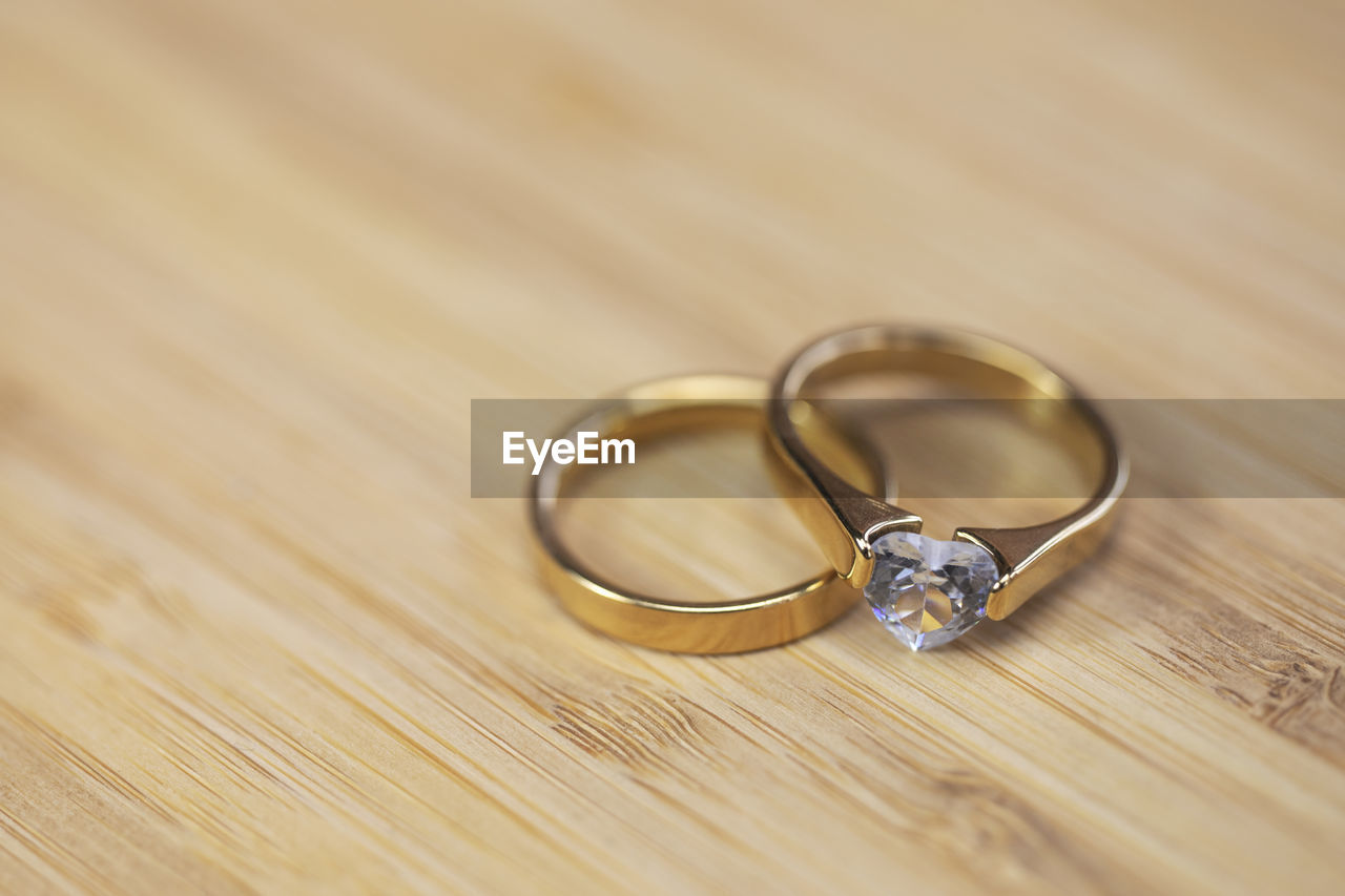 ring, wedding ring, jewelry, love, wedding, life events, emotion, positive emotion, engagement ring, event, celebration, gold, togetherness, married, fashion accessory, romance, engagement, dedication, diamond, diamond ring, jewellery, two objects, bonding, newlywed, copy space, metal, platinum, wood, bride, indoors, close-up, wealth, selective focus, wedding ceremony, ceremony, affectionate, luxury, silver, circle, beginnings, unity, shiny