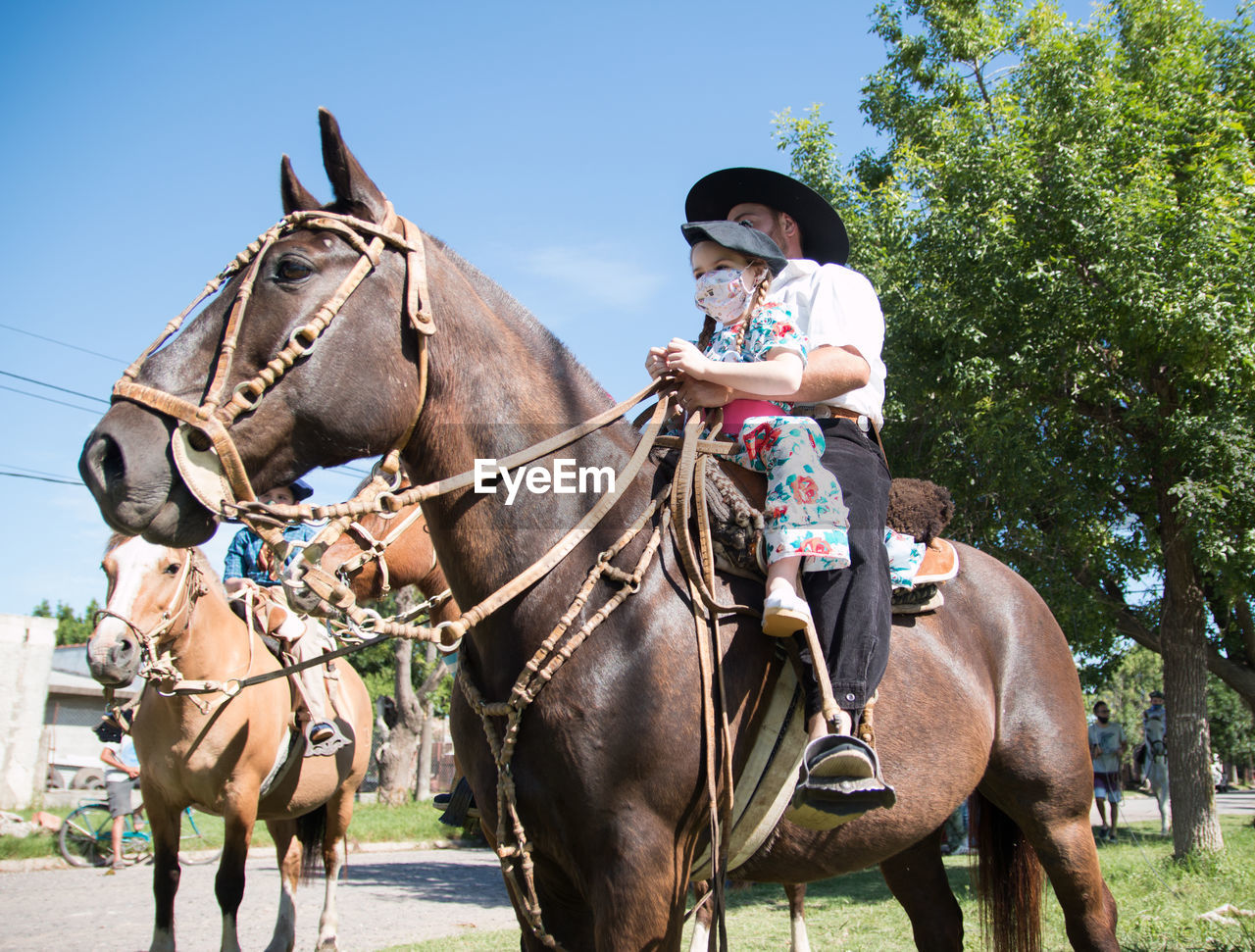 Argentinian father and daughter riding horse together