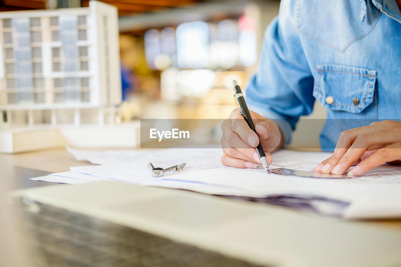 Midsection of female architect working at desk