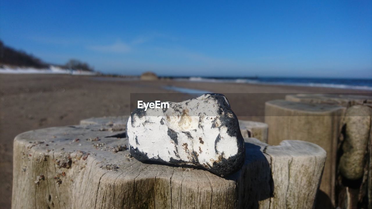 CLOSE-UP OF WOODEN POST ON BEACH