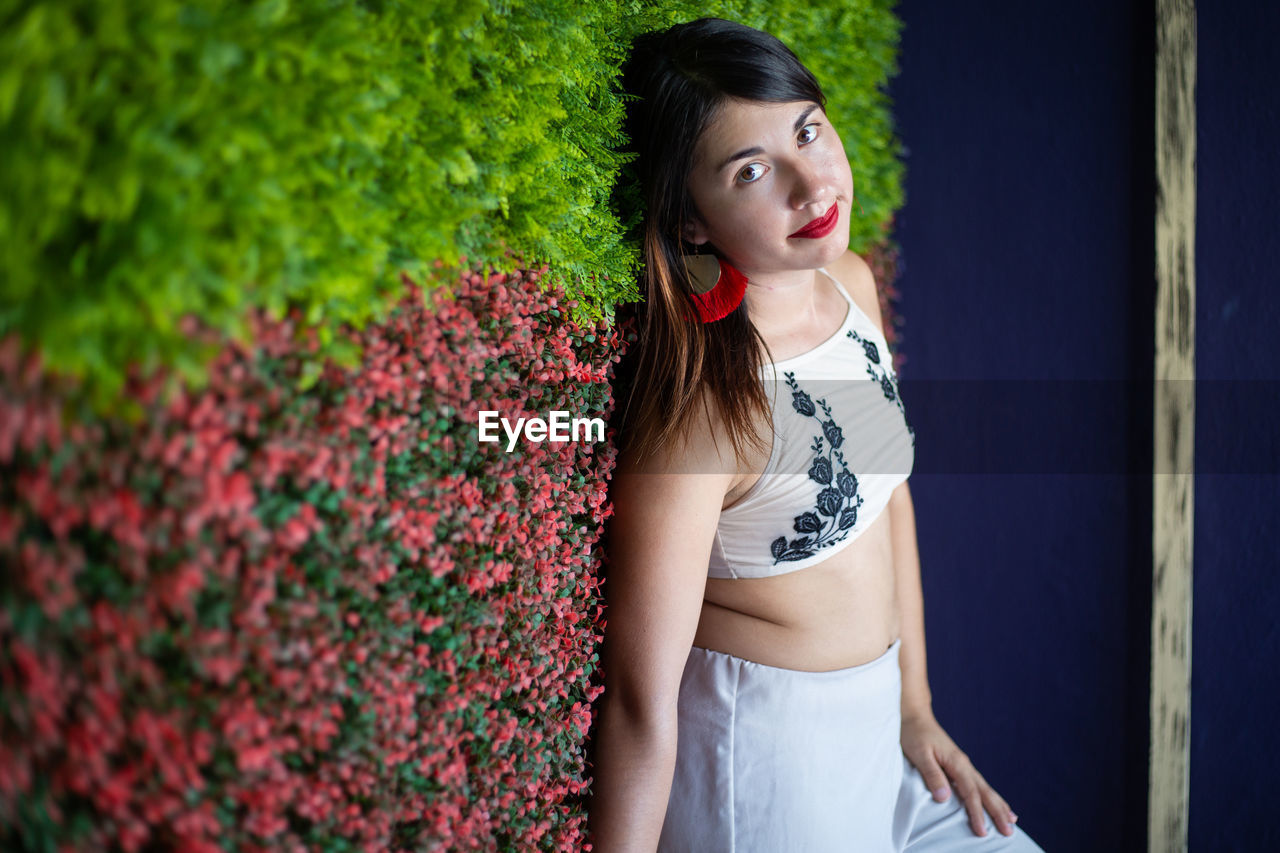 Beautiful young woman standing by flowering plants