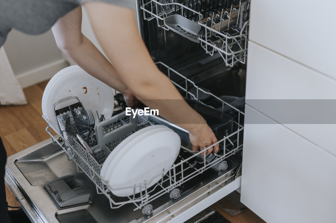 Woman putting dirty dishes in dishwasher