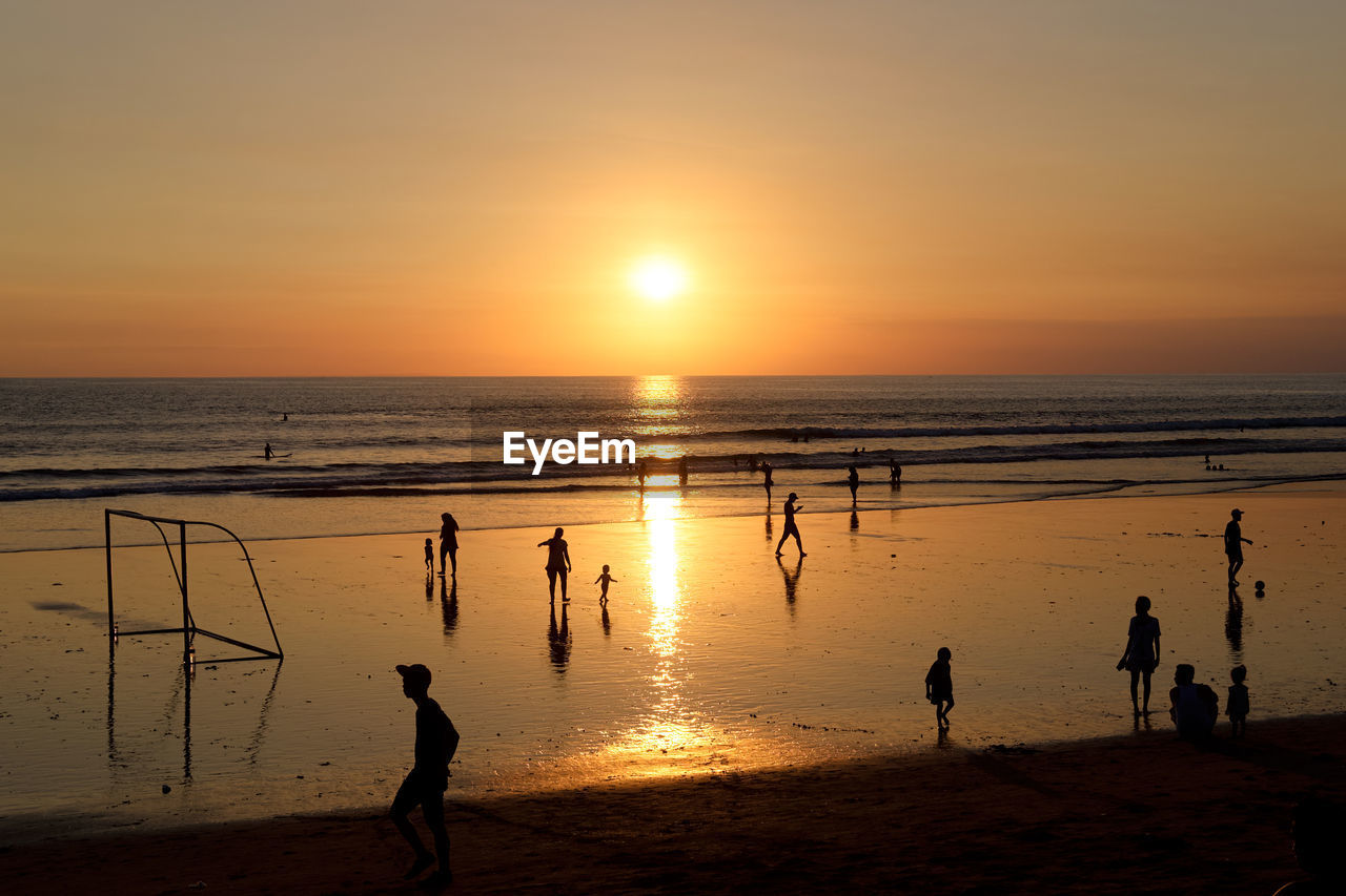 Silhouette people on beach against sky during sunset