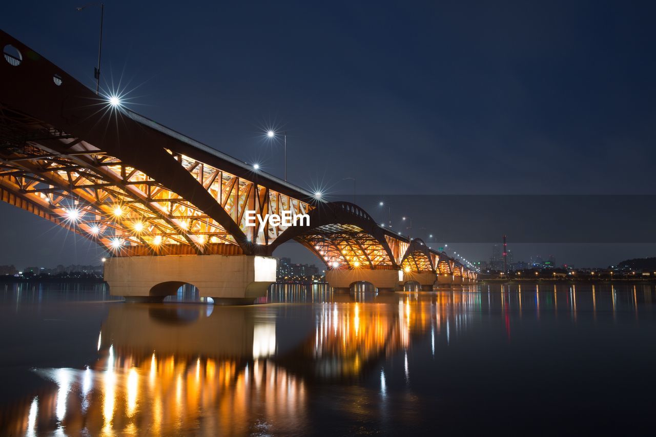 Illuminated seongsan bridge over han river against blue sky at night