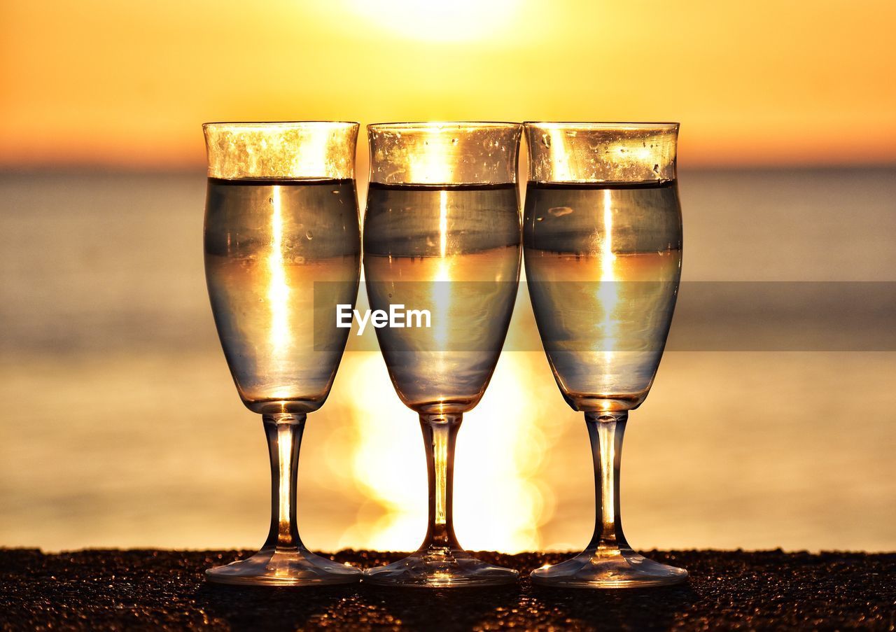 CLOSE-UP OF BEER IN GLASS AGAINST SUNSET SKY