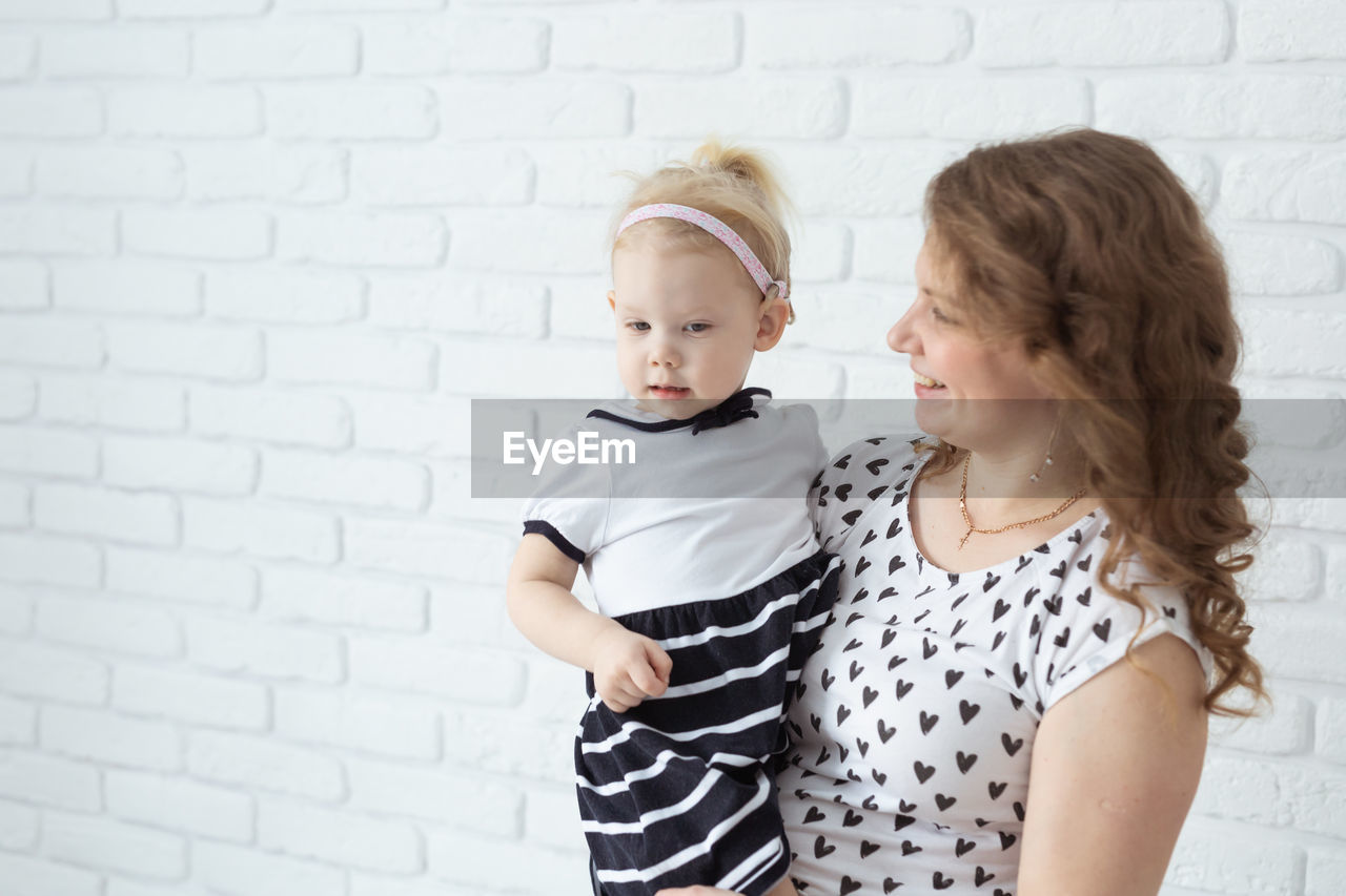 Mother and daughter standing in front of wall