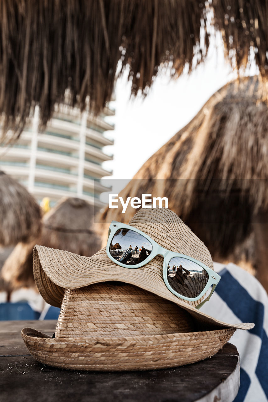 Close-up of sunglasses with hats on table at beach