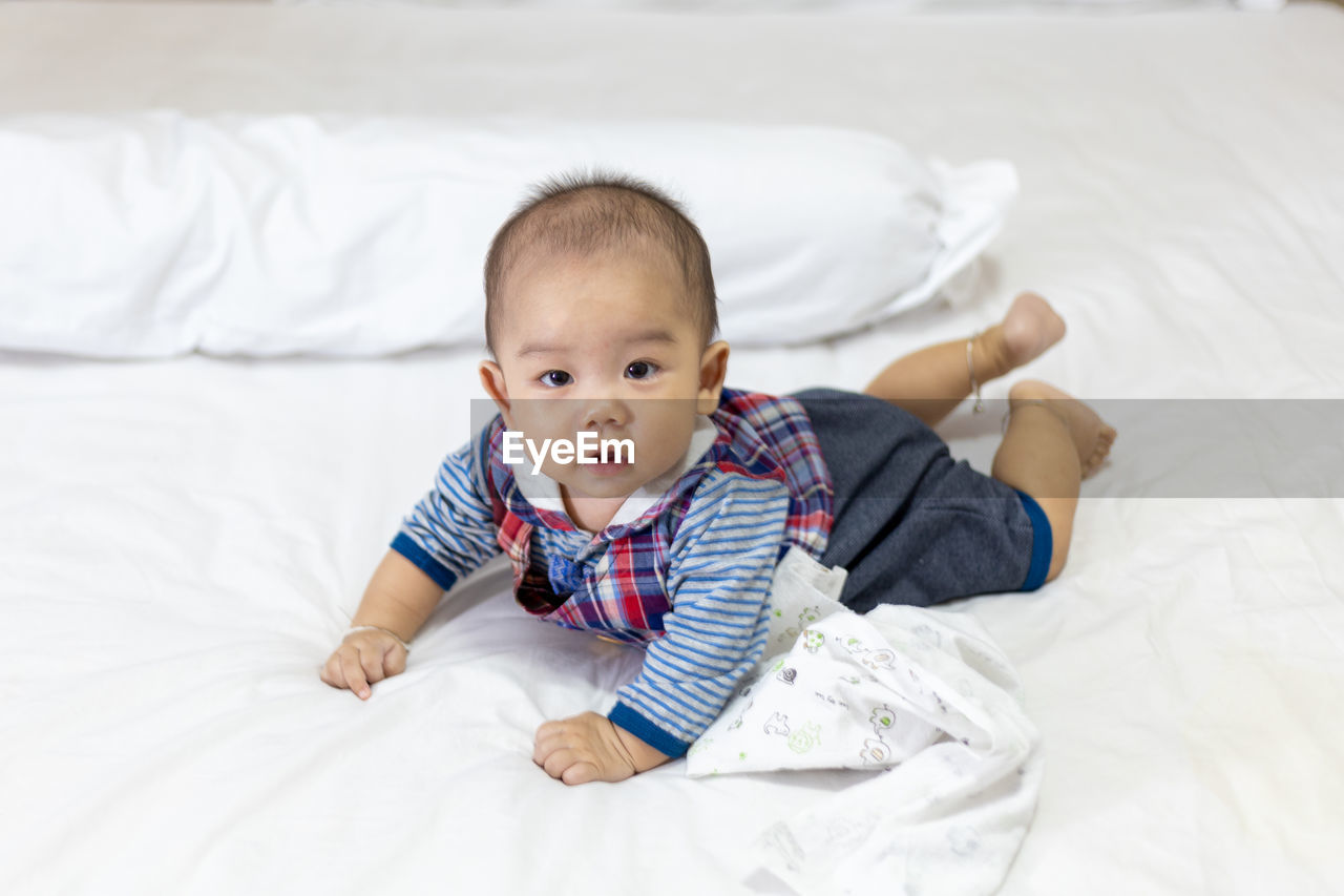 Portrait of cute baby lying on bed