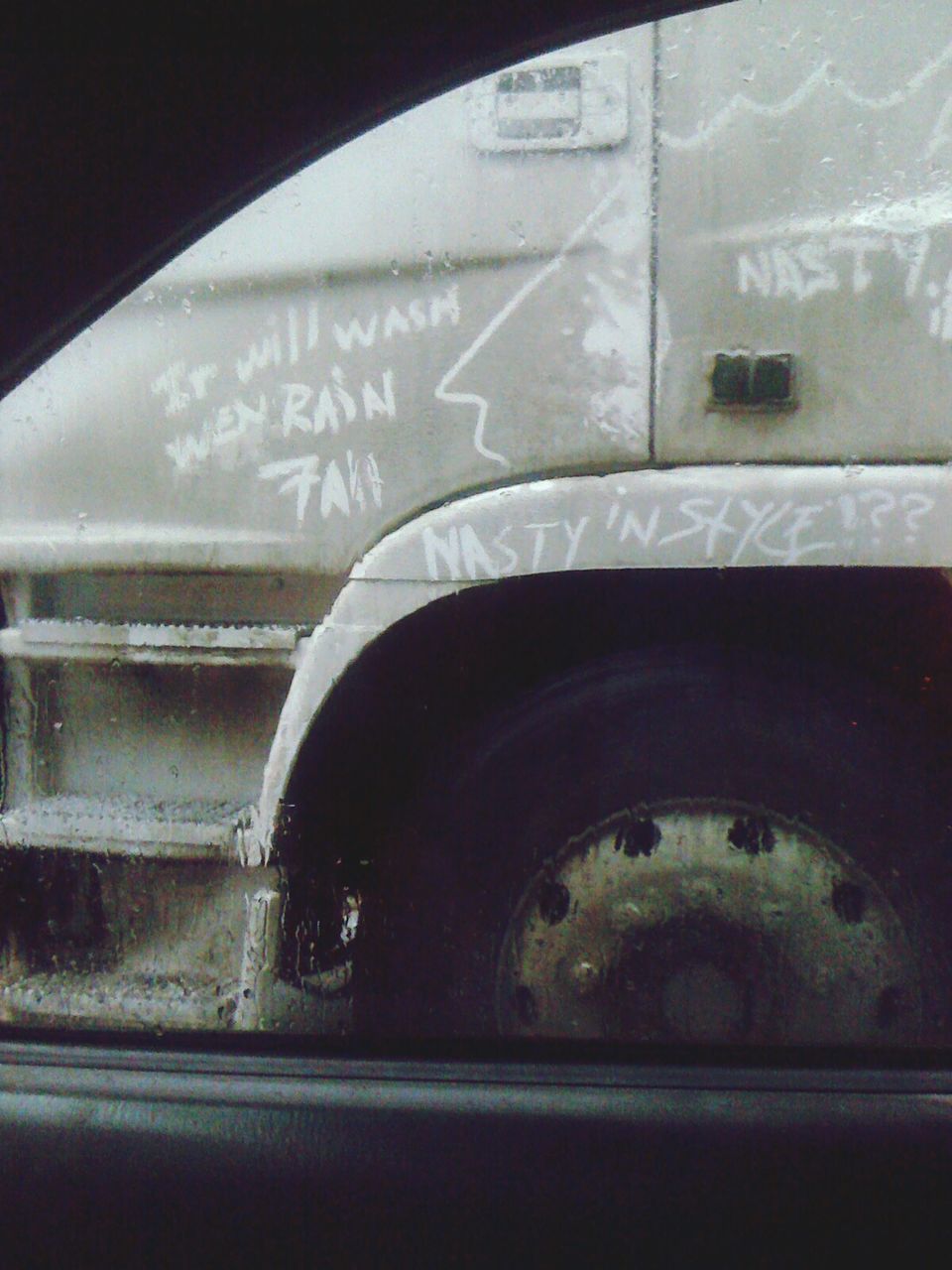 Text on vehicle seen through wet car window during rainy day