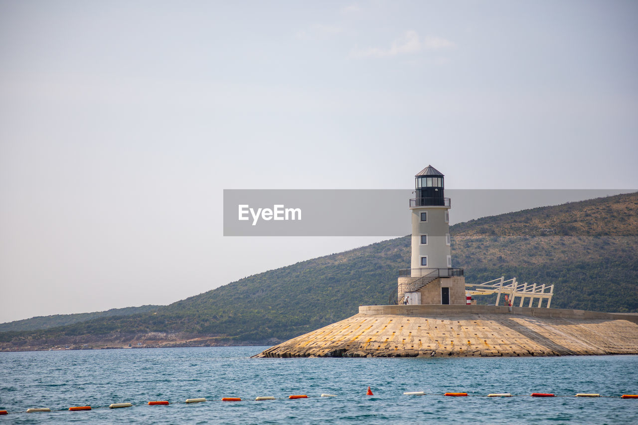 LIGHTHOUSE BY BUILDING AGAINST SKY