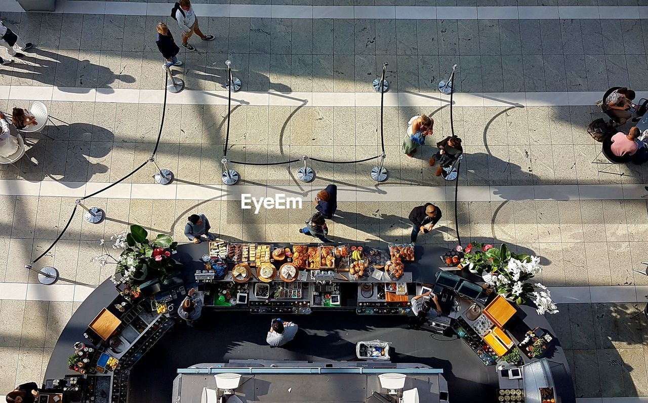 HIGH ANGLE VIEW OF PEOPLE ON ROAD AGAINST CITY