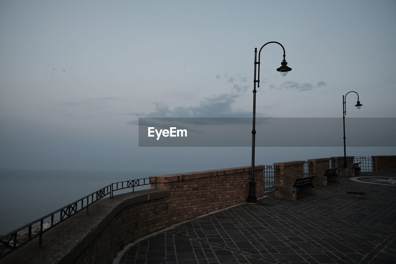 Street light by sea against sky