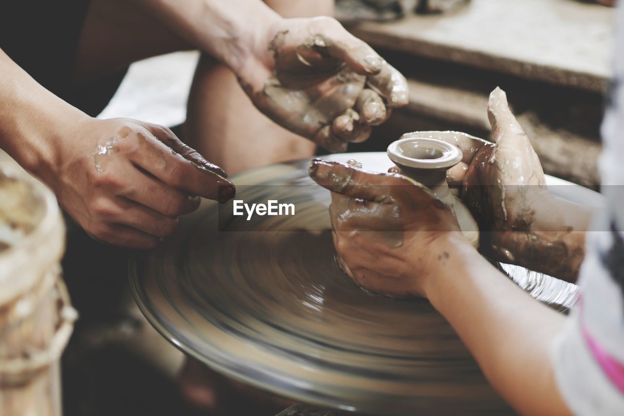 Cropped image of people working on pottery wheel