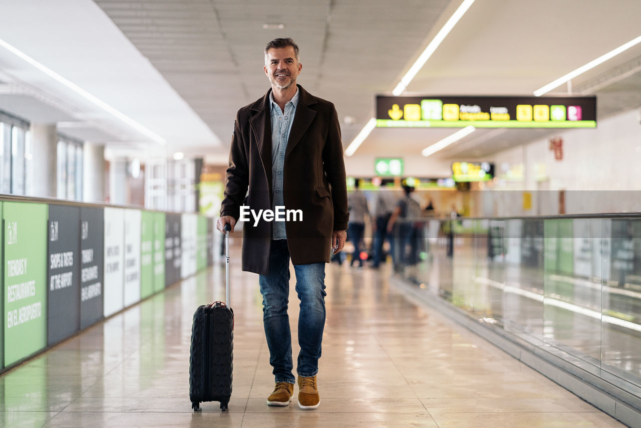 Full length portrait of young man standing at airport