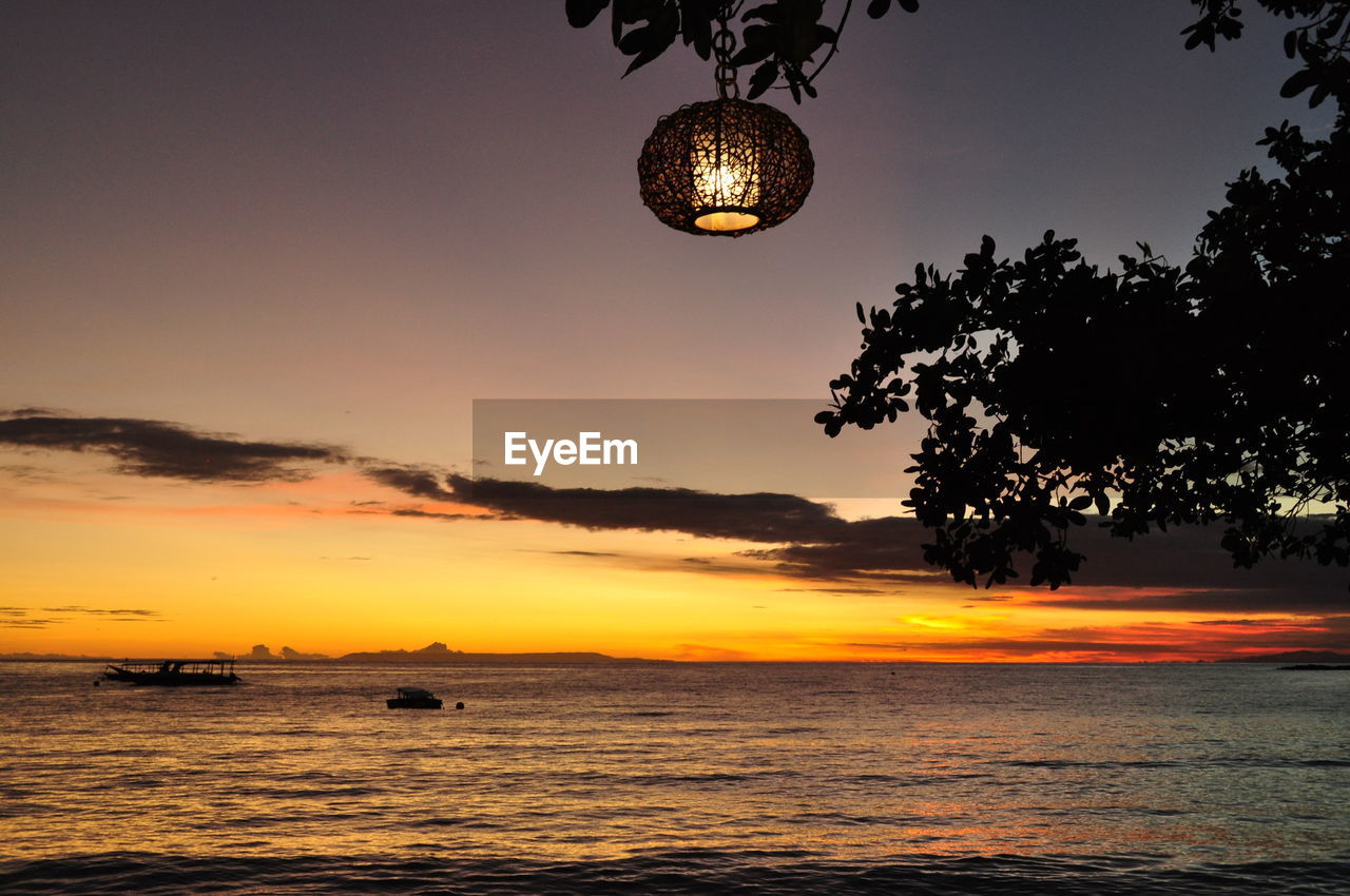 SILHOUETTE TREES BY SEA AGAINST SKY AT SUNSET