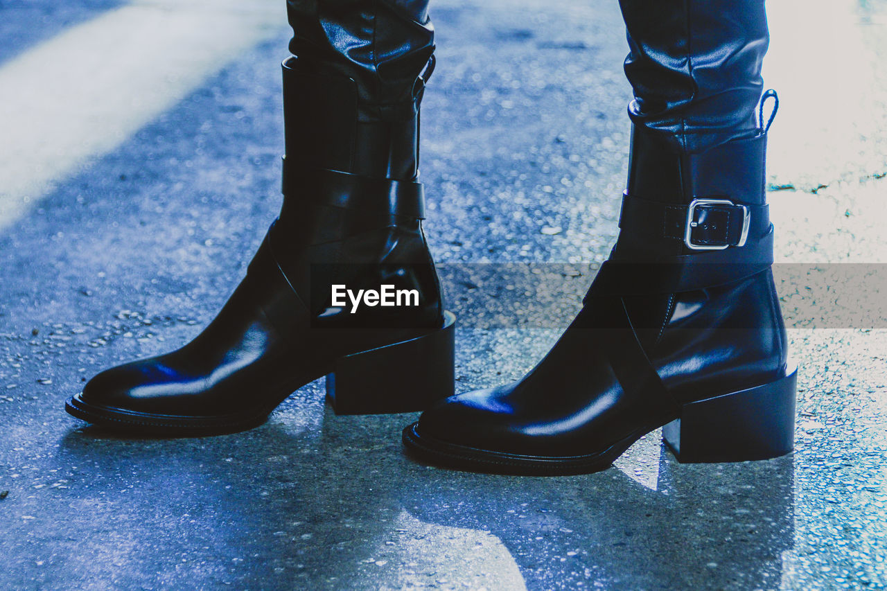 Low section of woman wearing boots while standing on road