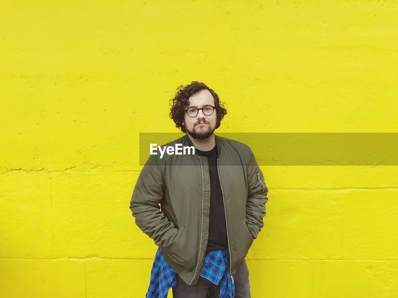 PORTRAIT OF A SMILING YOUNG MAN STANDING AGAINST YELLOW WALL