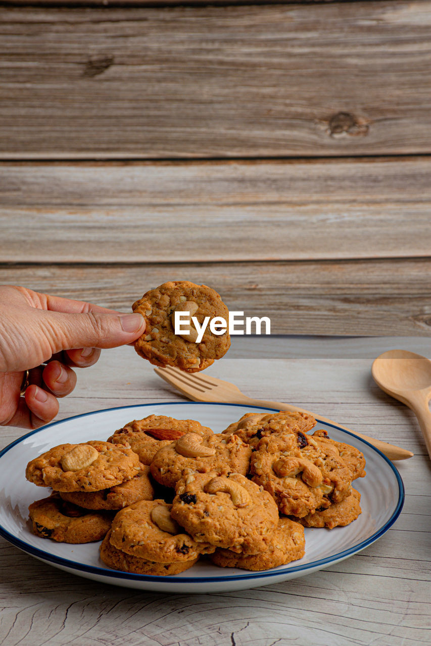 Homemade almond cookies in ceramic white plate on wood table background.