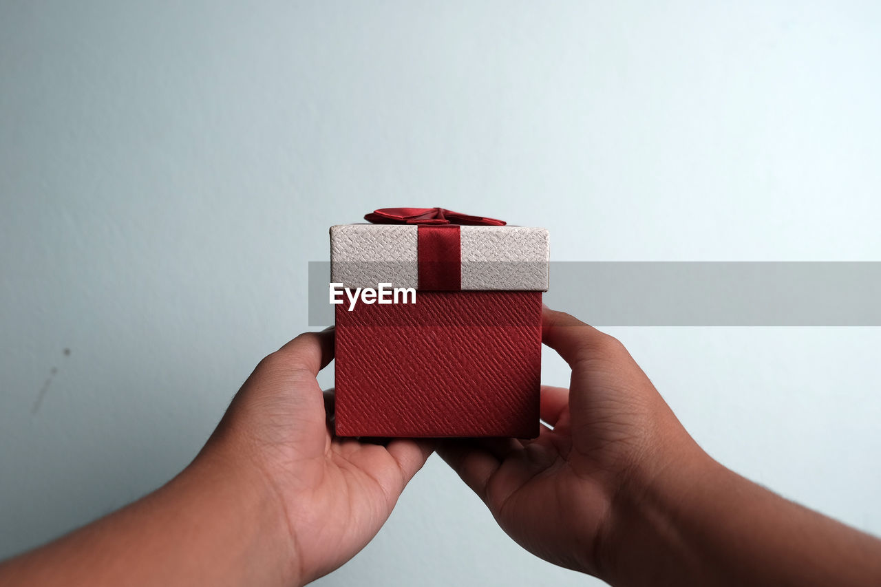 Close-up of hand holding christmas present against white background