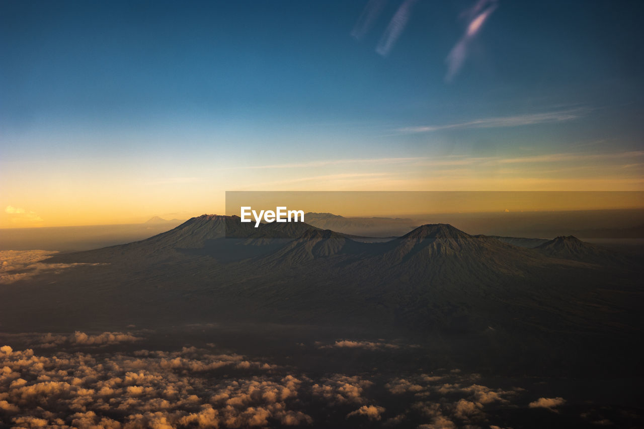 AERIAL VIEW OF SNOWCAPPED MOUNTAINS AGAINST CLOUDY SKY