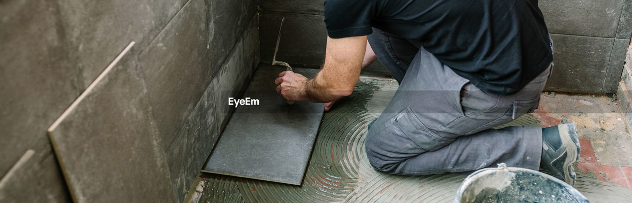 High angle view of mason worker applying tiles