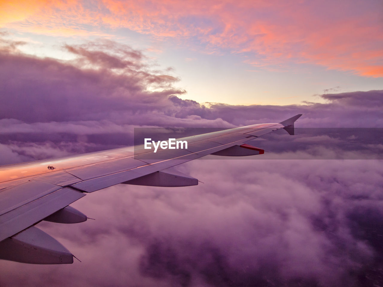 Cropped image of airplane flying in cloudy sky at sunset