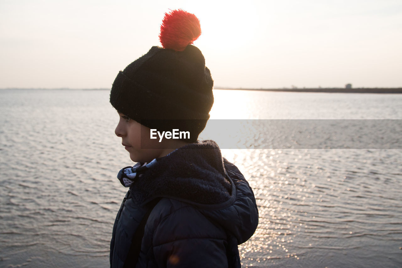 Lovely boy wearing winter clothes next to the sea