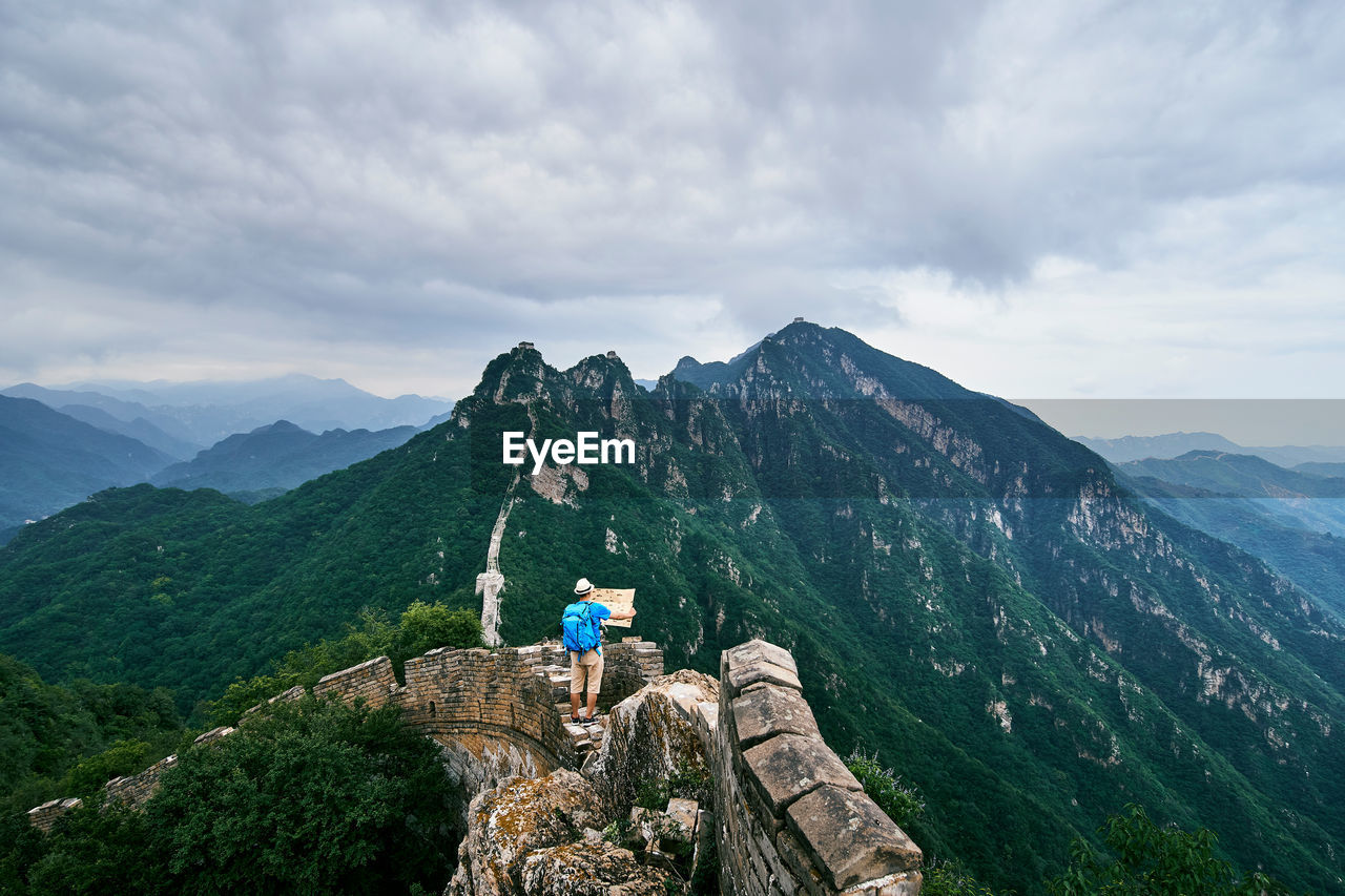 High angle view of man holding map while standing on great wall of china