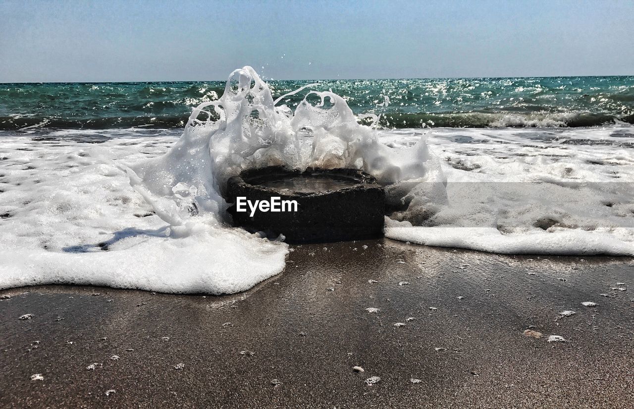 Waves on beach against clear sky