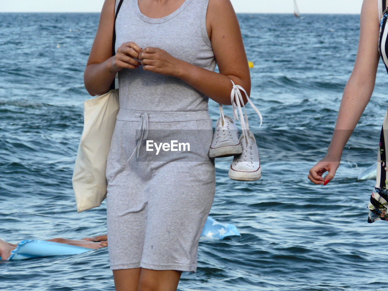 MIDSECTION OF WOMAN STANDING ON SEA