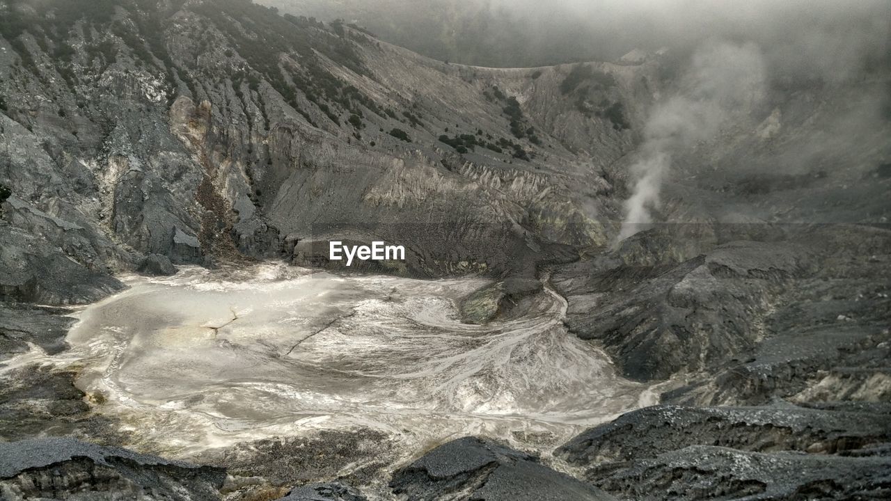 Hot spring emitting smoke by mountains