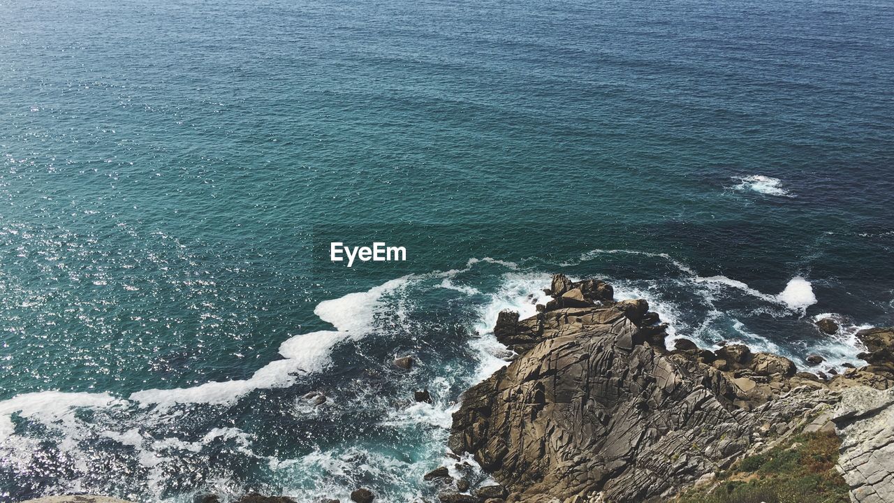 High angle view of waves breaking on cliff