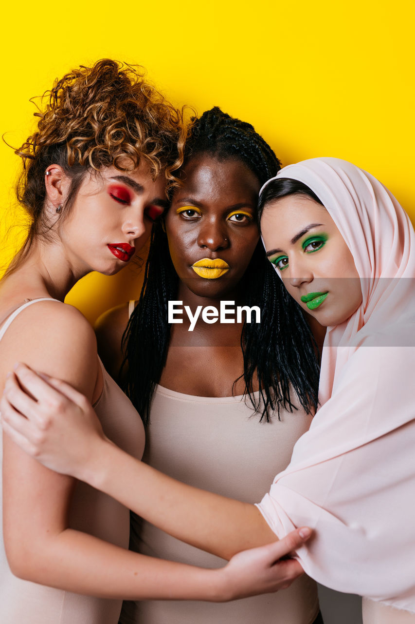 Portrait of women sitting against yellow background