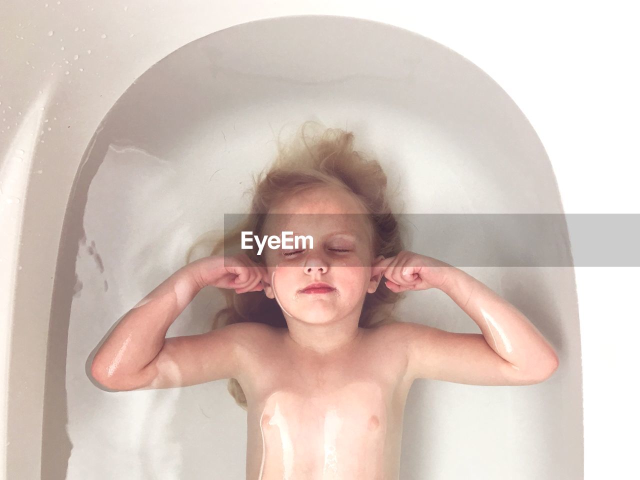 Cute young girl sleeping in bathtub